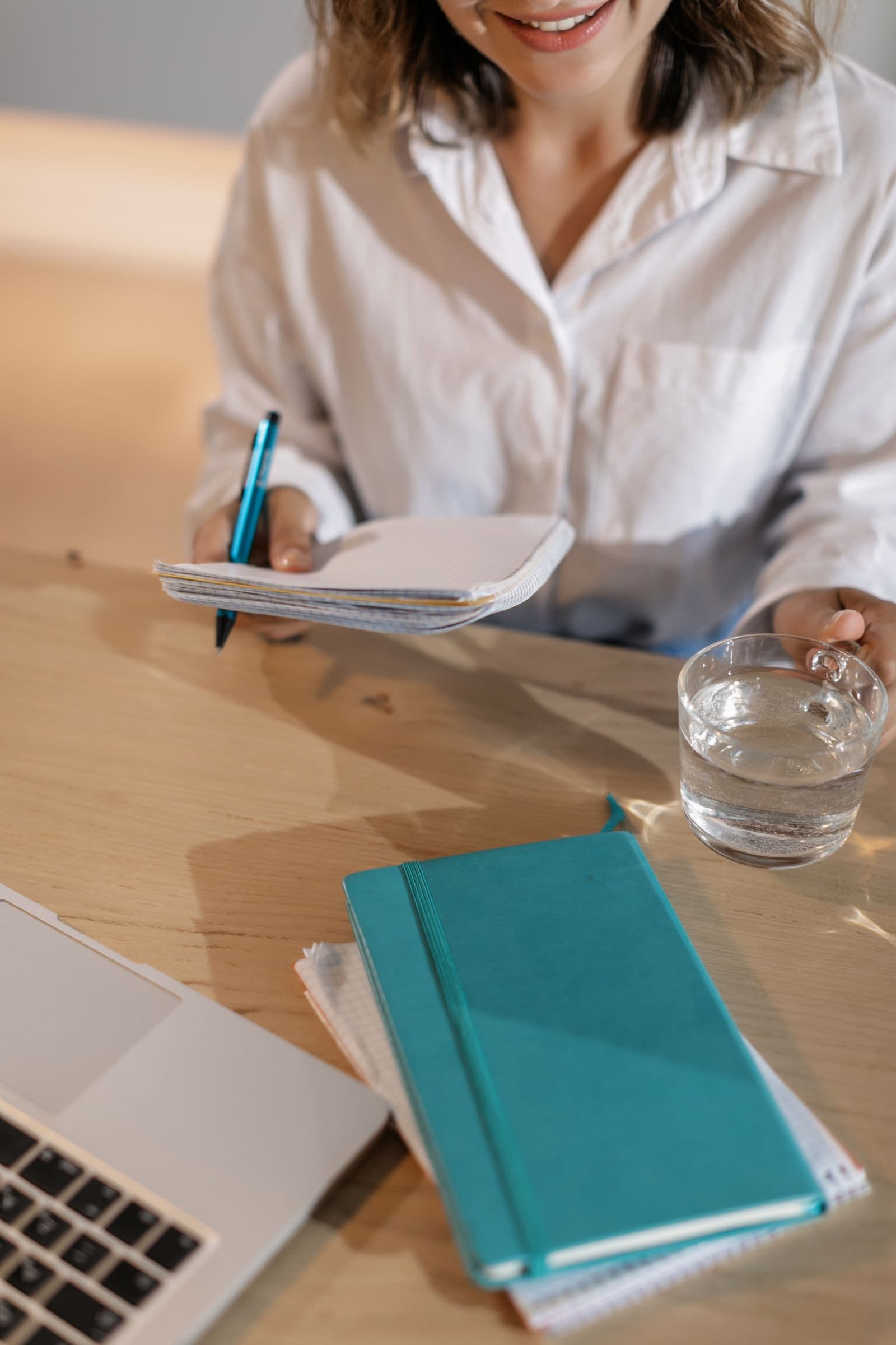 Smiling while jotting notes alone at a desk before a call